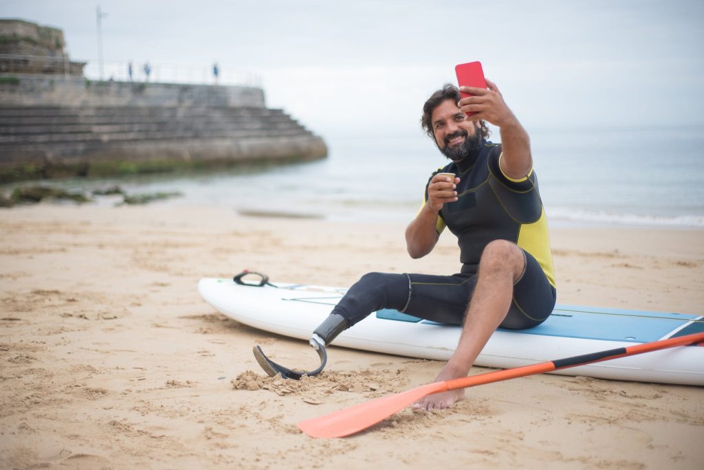 A Man Taking a Selfie on a paddle board on the Beach.