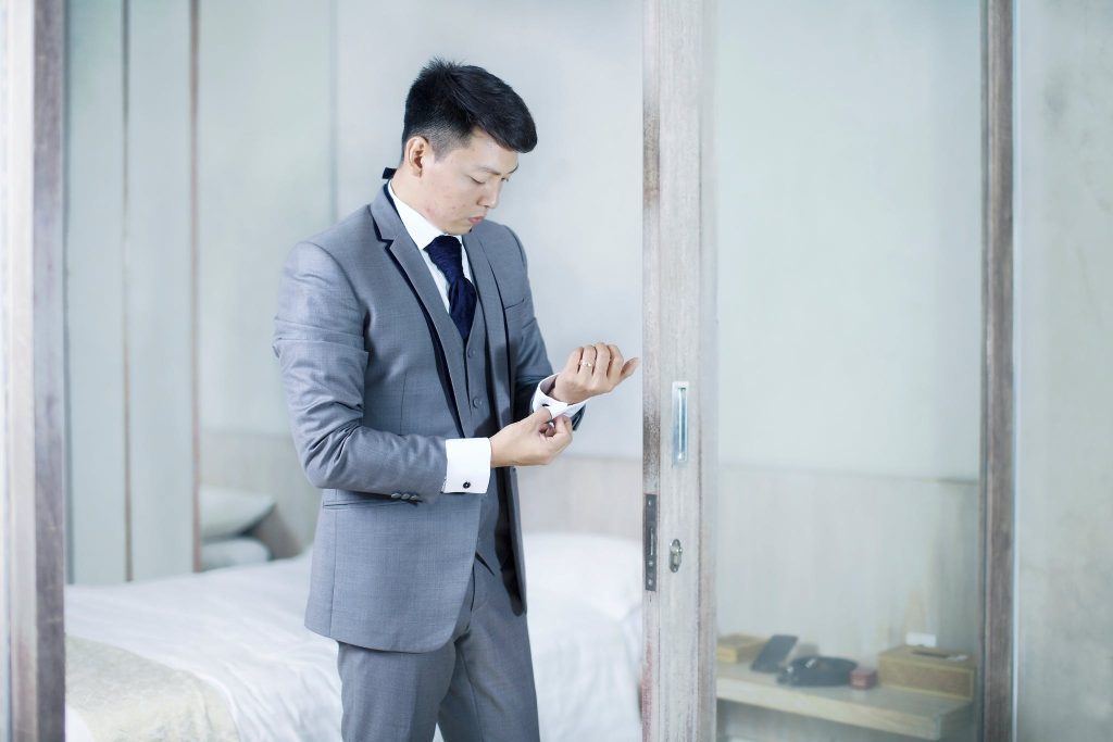 Man in a grey suit Standing Beside Glass Wall.