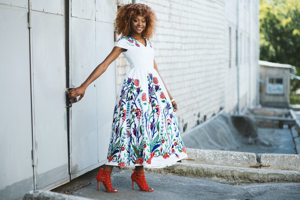 Woman in floral White and Multicolored Midi Dress Holding Door.