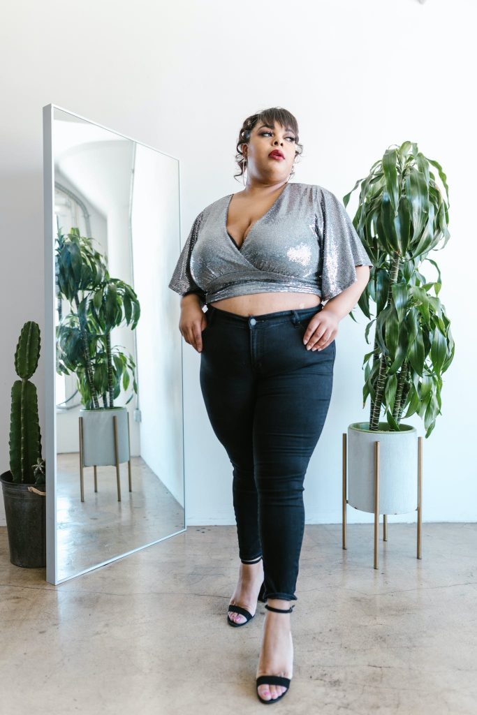 Woman Wearing a Crop  and high waisted jeans Top Standing Beside a Mirror.